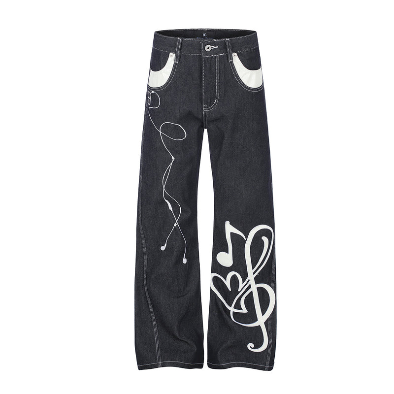 Jean baggy noir en denim brut à jambes larges, avec appliqué brodé blanc en cuir représentant une note de musique et une clé de sol sur le devant de la jambe et b