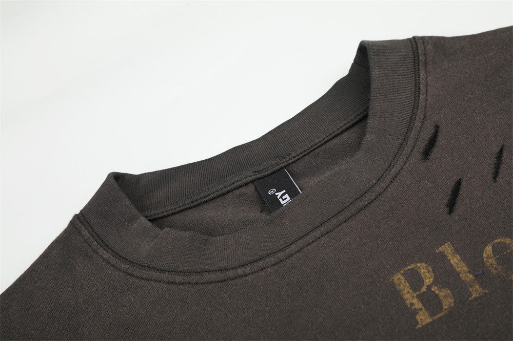 Close-up of black crewneck collar with distressed shoulder tears and printed lettering