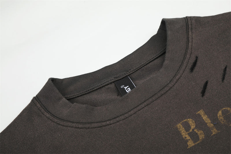 Close-up of black crewneck collar with distressed shoulder tears and printed lettering