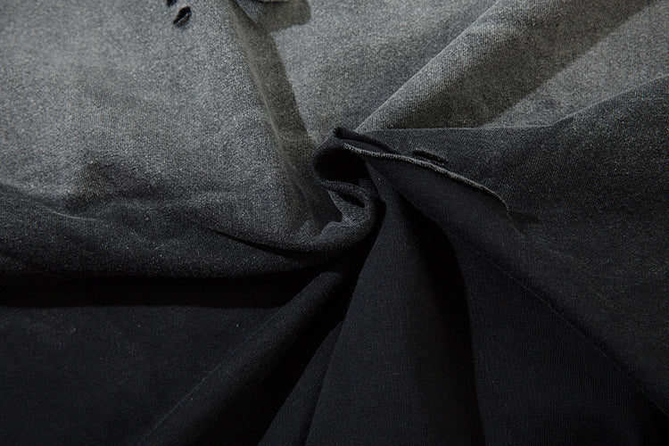 A close-up of a distressed black and gray fabric, with slight twist and texture variations, reminiscent of anime streetwear. Frayed edges and shadows suggest the soft, flexible nature of the Death Note Limited Edition Long Sleeve Shirt's artistic hem.