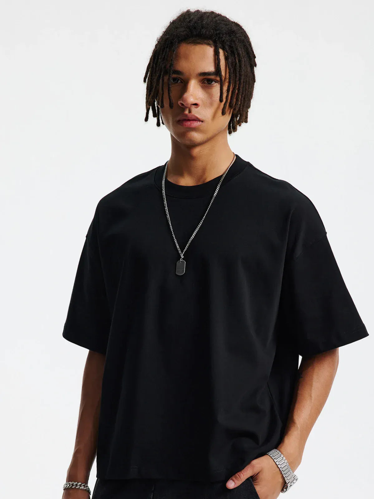 Wearing the Custom Anime Character Black T-Shirt – a personalized 230GSM 100% cotton tee – someone with medium-length dreadlocks, a rectangular pendant necklace, and bracelet stands against a plain light background.