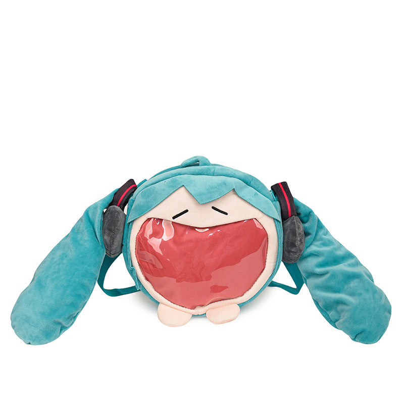 The Seakoff Cute Anime Hatsune Miku Backpack is a plush ita bag with stylized eyes, teal pigtails, and a large open mouth. Perfect for anime fans, it features a transparent front pocket and adjustable straps, capturing the iconic Miku style!.