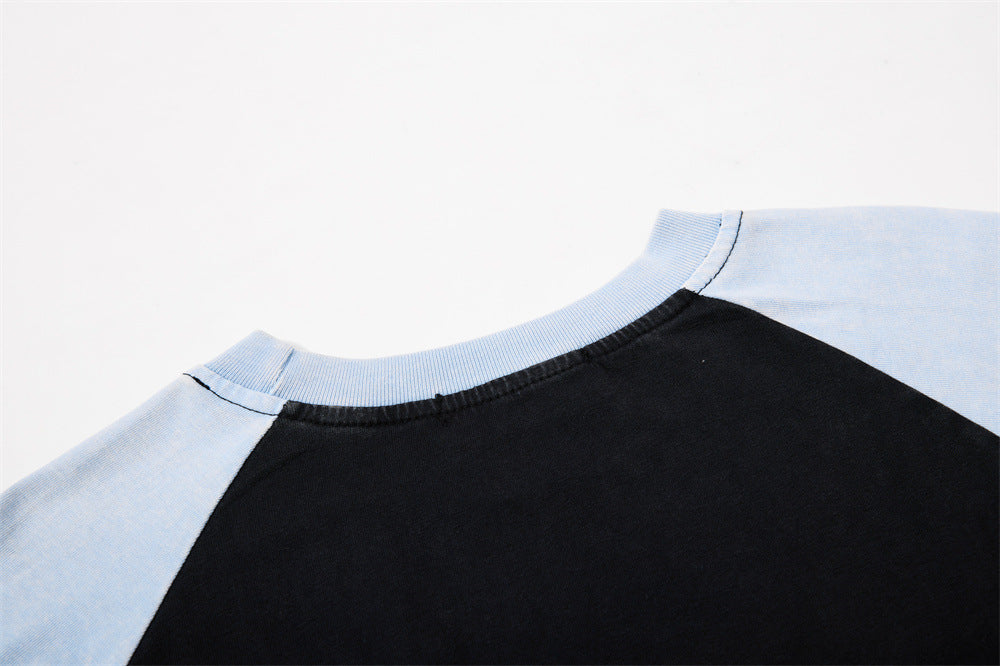 Close-up of crew neck and raglan shoulder seams on black and light blue long sleeve tee