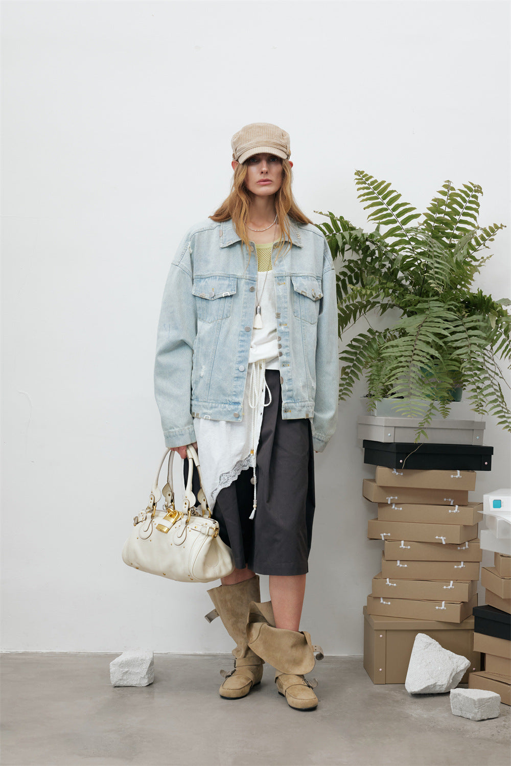 Full-length model view wearing a cropped light wash denim jacket with chest pockets and distressed detailing