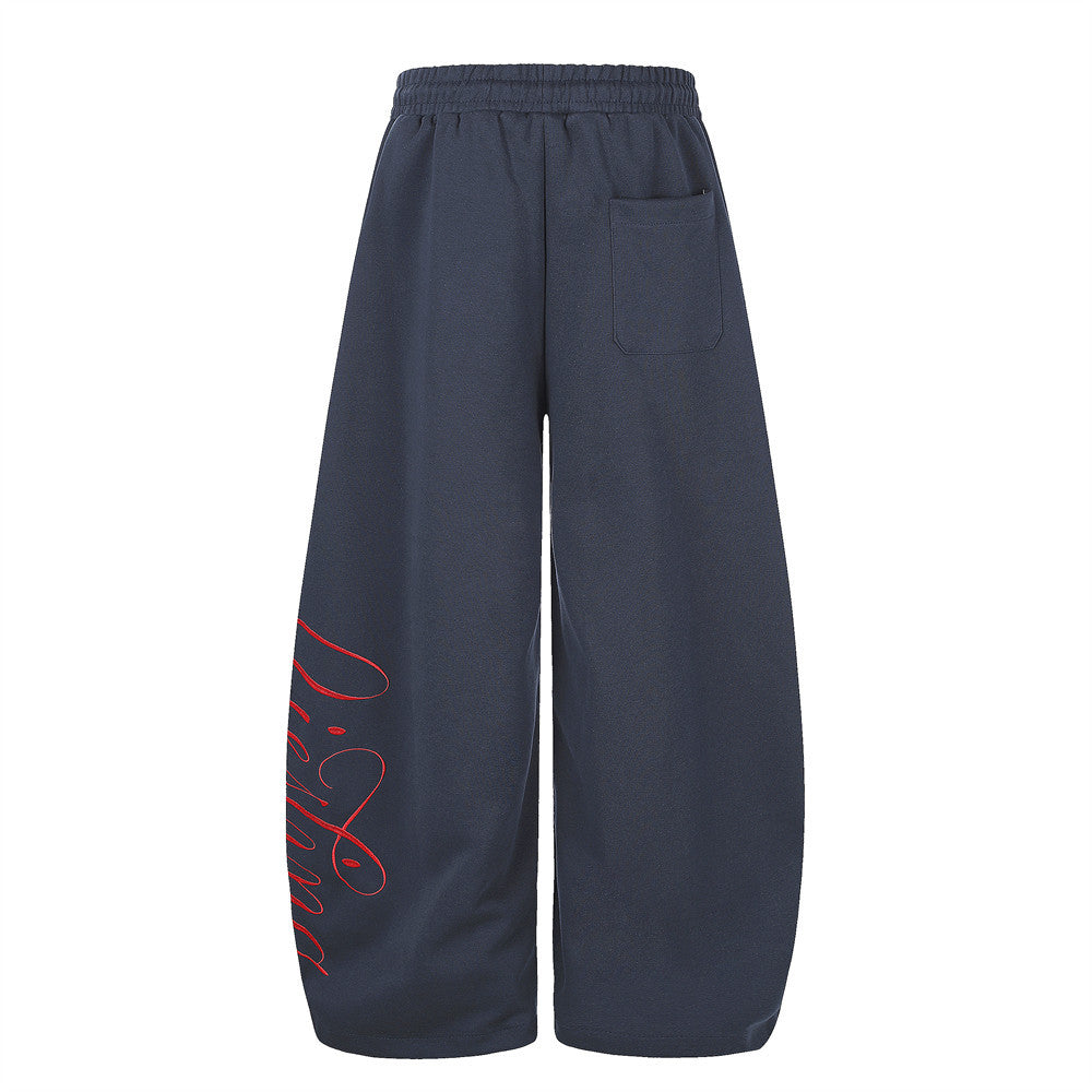 Back view of navy wide-leg sweatpants with rear pocket and red script print along one leg