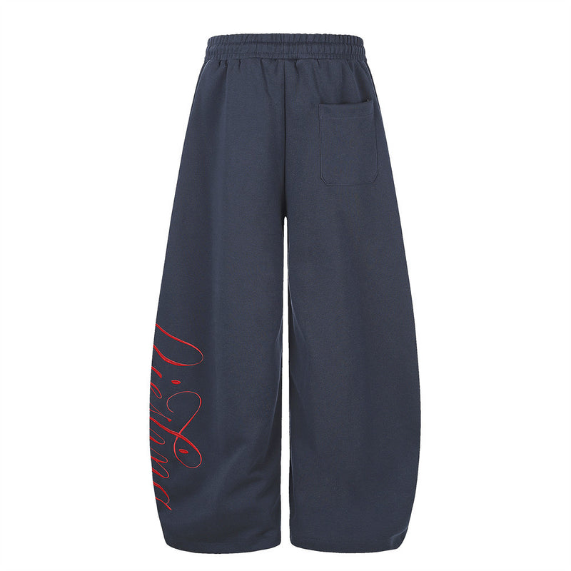 Back view of navy wide-leg sweatpants with rear pocket and red script print along one leg