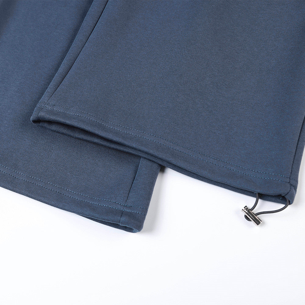 Close-up of hem on navy track pants with drawstring-adjustable ankle opening