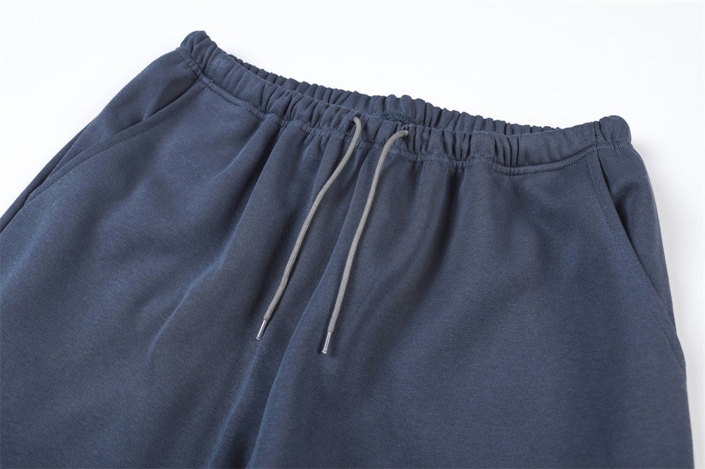 Close-up of navy track pants waistband with elastic gather and gray drawstring cords