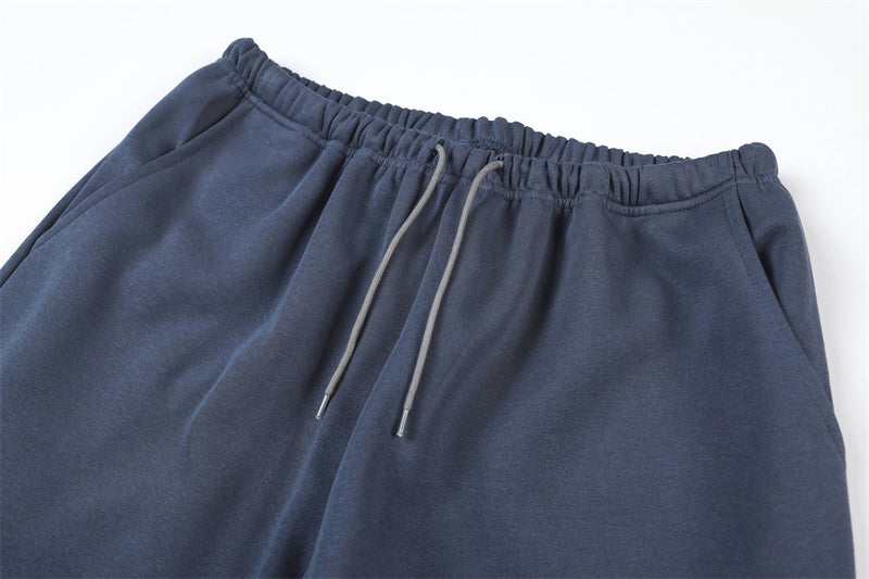 Close-up of navy track pants waistband with elastic gather and gray drawstring cords