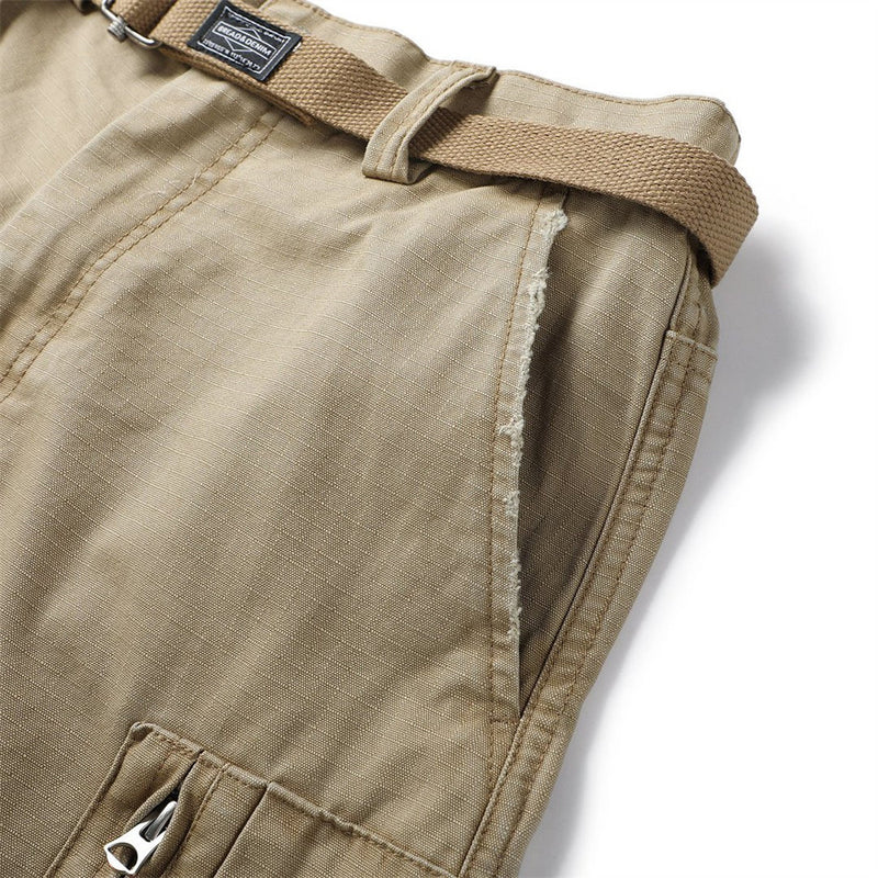 Close-up of khaki cargo shorts side seam showing frayed trim and belt at the waist