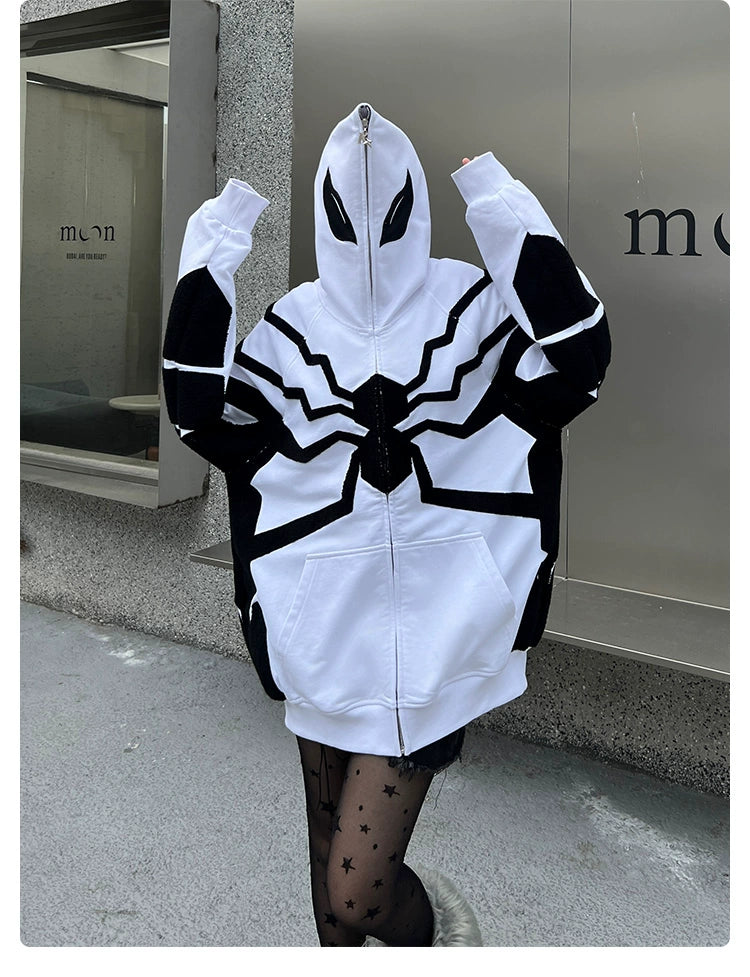 A person showcases their bold style in a Seakoff Venom-Inspired White Hoodie, featuring black web-like patterns and a unique full zip-up hood resembling a spider mask, made from 400GSM cotton. They pair it with star-patterned tights while standing on a concrete surface.