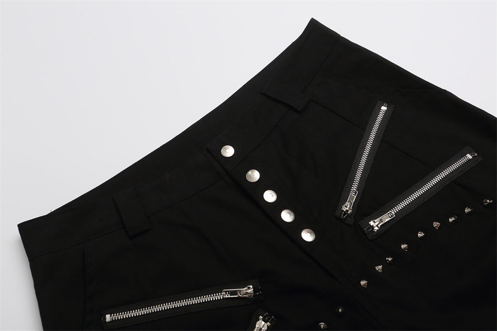 Close-up of black shorts front waist with button fly, zippers, and stud detail