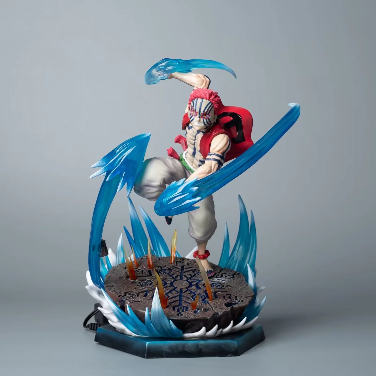 The Rengoku Kyojuro Demon Slayer Figure is a 26cm PVC anime collectible featuring dynamic ice powers and light-up effects. It showcases the Flame Hashira with red spiky hair, tribal face markings, white pants, and a red vest, dynamically poised on a decorative base.