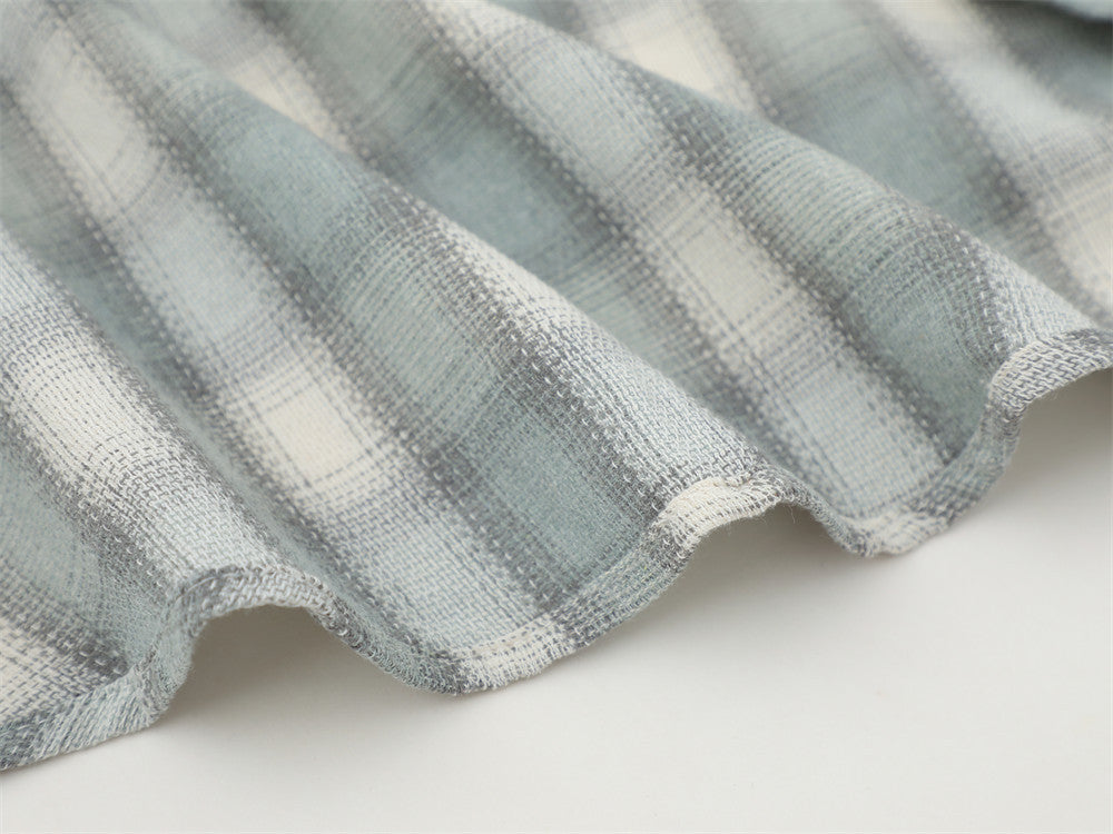 Close-up of the curved hem on a light gray plaid flannel shirt
