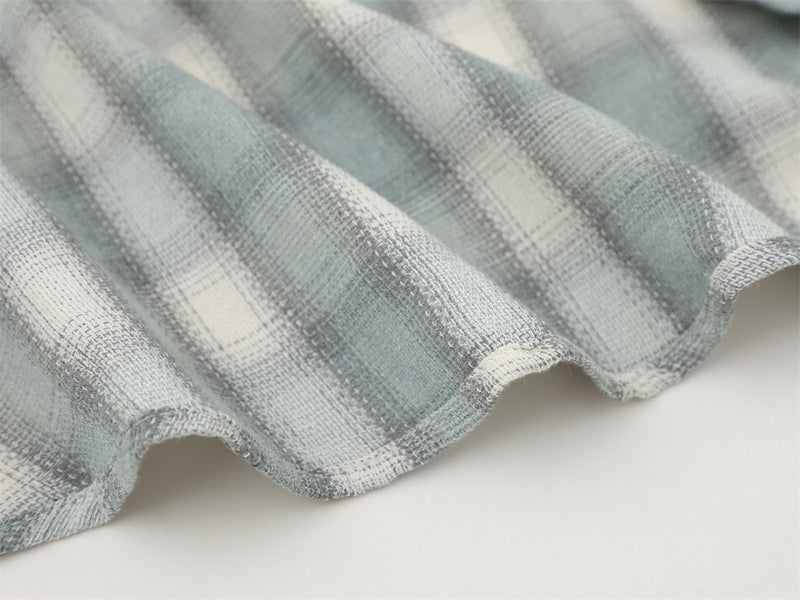Close-up of the curved hem on a light gray plaid flannel shirt