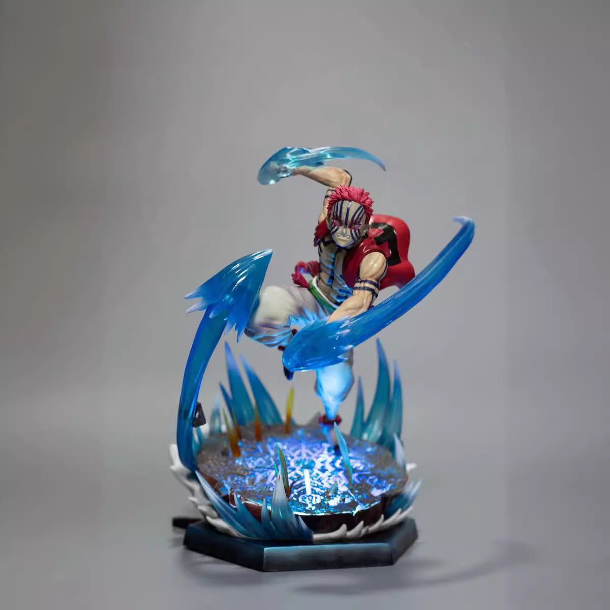 The Rengoku Kyojuro Demon Slayer Figure is a 26cm PVC anime collectible by Demon Slayer, showcasing the Flame Hashira mid-air with dynamic ice powers and light-up effects on a decorative base, set against a plain gray background.