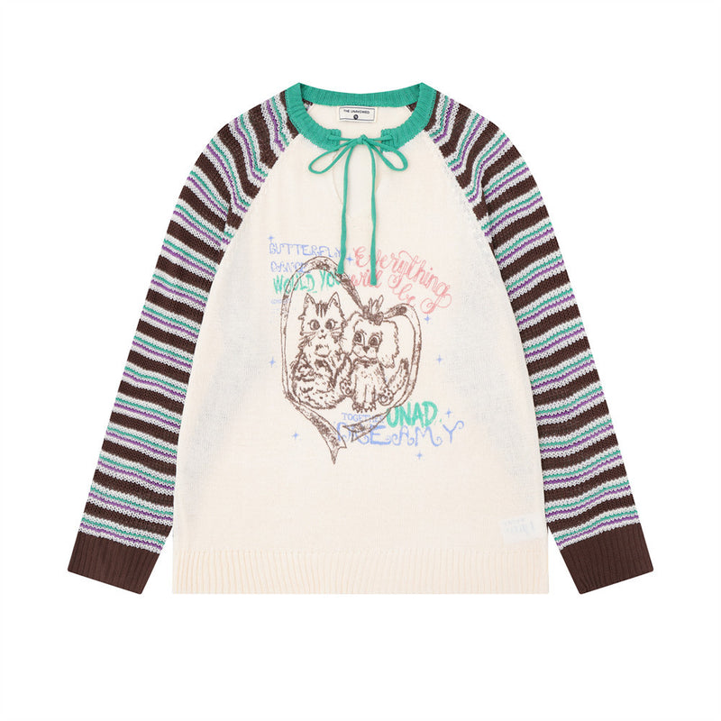 Pull-over en maille crème à empiècements color block, manches raglan rayées multicolores et motif cartoon sur la poitrine