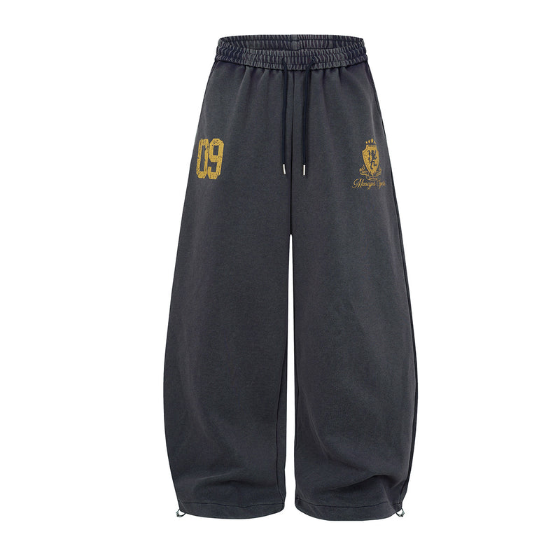 Oversized wide-leg acid-wash sweatpants with varsity 09 number print and heraldic crest graphic in charcoal black