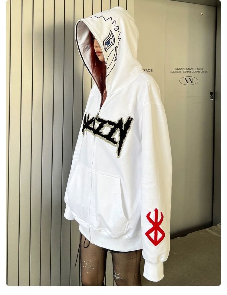 A person with long hair wears the Berserk Griffith-Inspired Hoodie, a large white zip-up sweatshirt featuring a stylized face on the hood, black text on the front, and a red Brand of Sacrifice symbol on the sleeve. They stand against a metallic wall in sheer black sparkly tights.