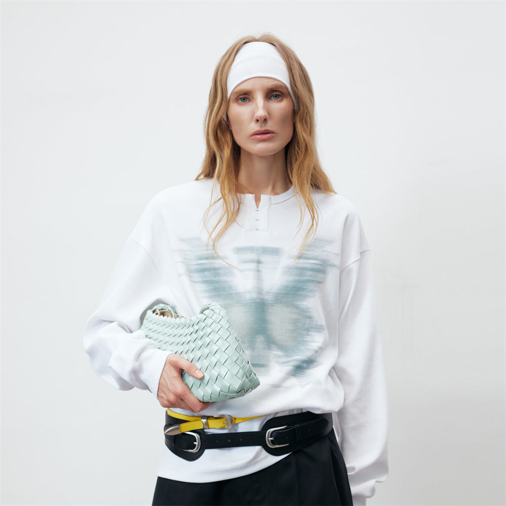 Oversized white long sleeve sweatshirt with teal motion-blurred butterfly graphic print and Henley button neckline