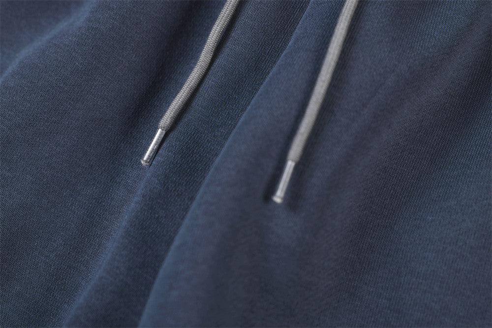 Close-up of gray drawstring tips on navy track pants fabric