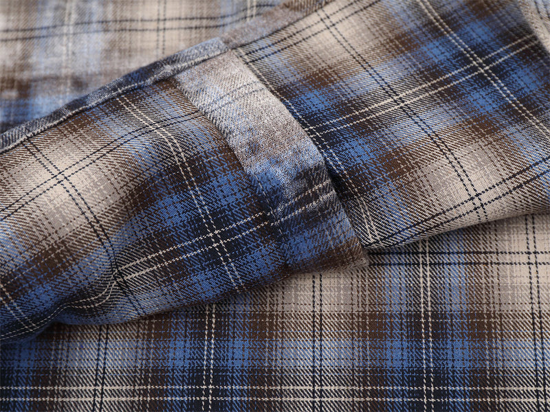 Close-up of plaid sleeve fabric and seam detail on blue and brown shirt