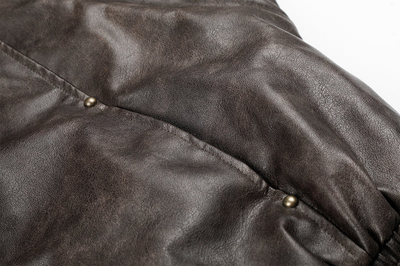 Close-up of brown faux leather sleeve seam with small metal snap details