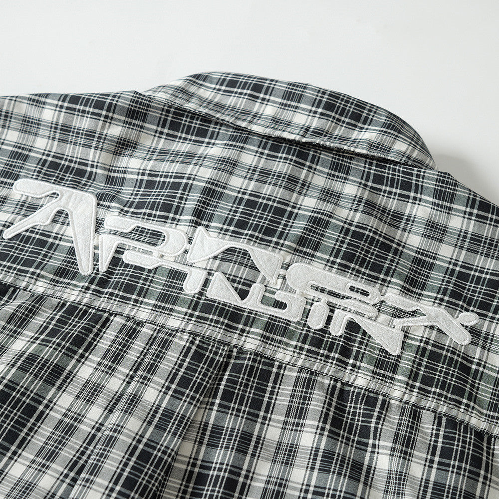 Close-up of white embroidered lettering on the back yoke of a black plaid shirt