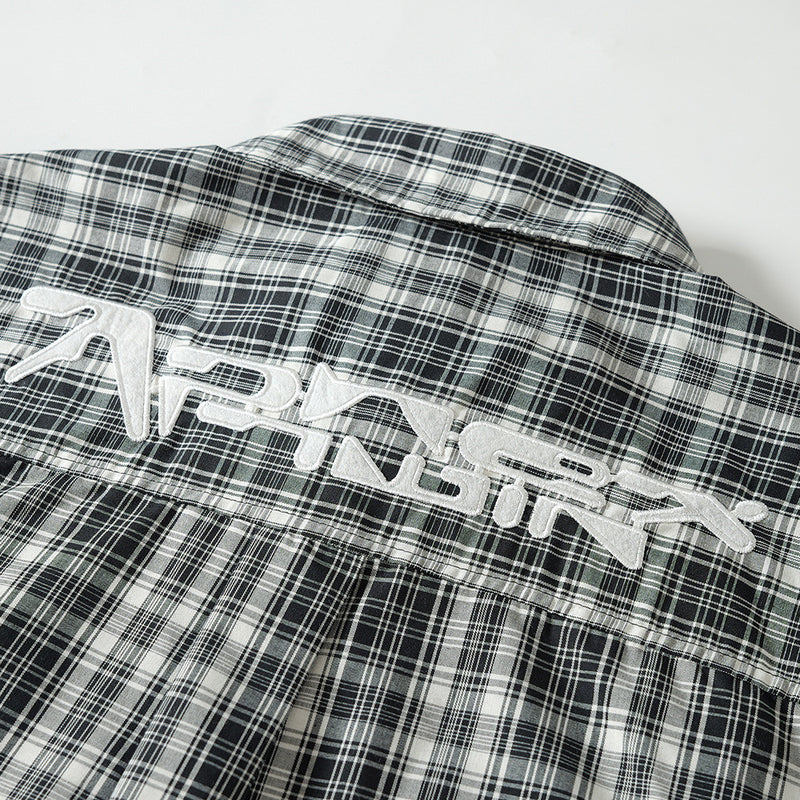 Close-up of white embroidered lettering on the back yoke of a black plaid shirt