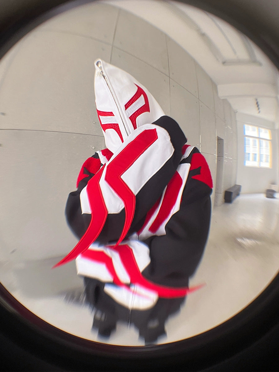 A person wearing a Seakoff Superhero-Inspired Hoodie, an oversized black, red, and white zip-up streetwear sweatshirt (400GSM), stands in a minimalist room with light gray walls and large windows. The fisheye lens adds a distorted, rounded effect perfect for comic book fans.