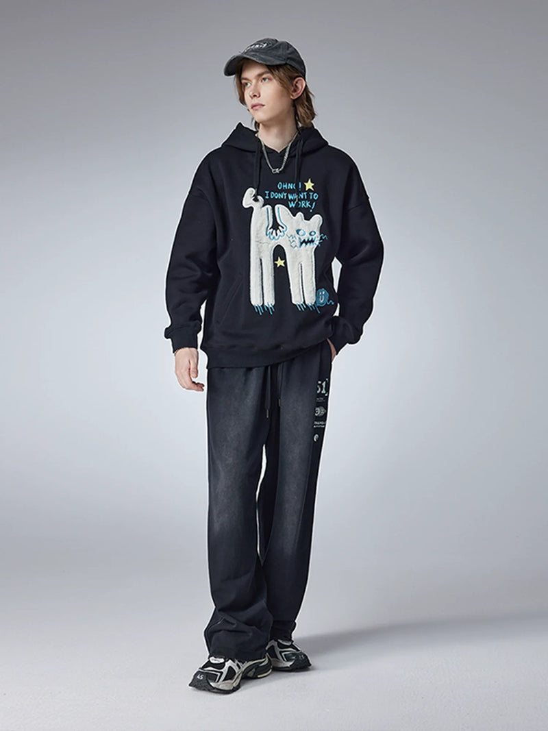 A person stands against a gray background wearing Seakoff's "Oh No! I Don’t Want to Work!" oversized hoodie featuring a lazy cat design, paired with dark pants, sneakers, and a baseball cap, perfectly embodying casual streetwear vibes.