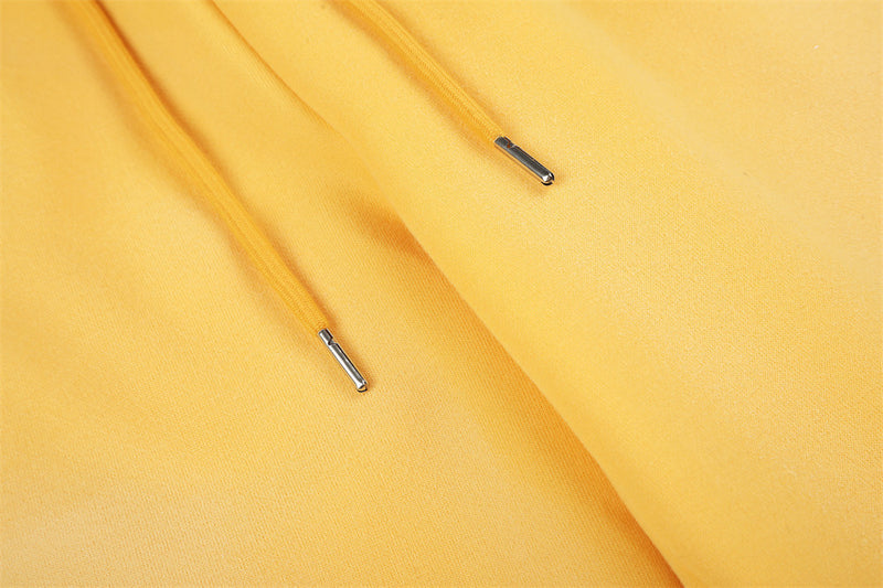 Close-up of yellow sweatpants drawstring tips on the front waistband
