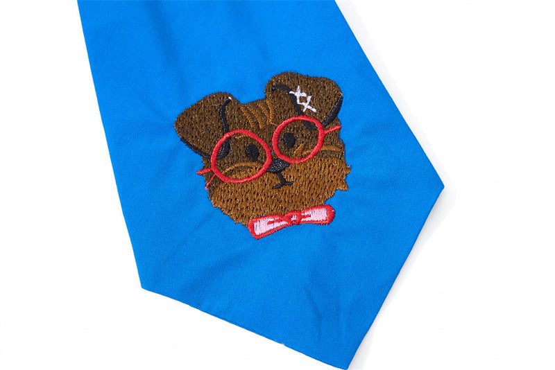 Close-up of blue tie with embroidered cartoon dog face and red glasses