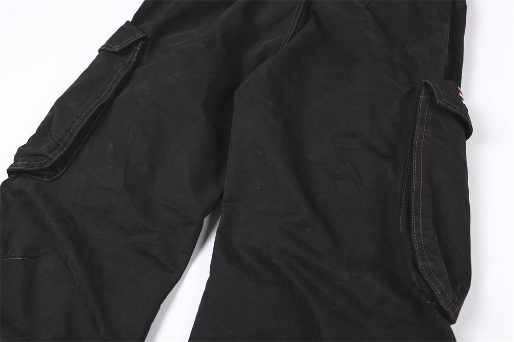 Close-up of black cargo pant thighs with side flap pockets and studded trim