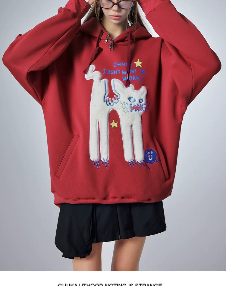Someone wears the Seakoff "Oh No! I Don’t Want to Work!" oversized graphic hoodie, showcasing a cute lazy cat design. Combined with a black skirt, it captures the essence of casual streetwear against a gray backdrop.