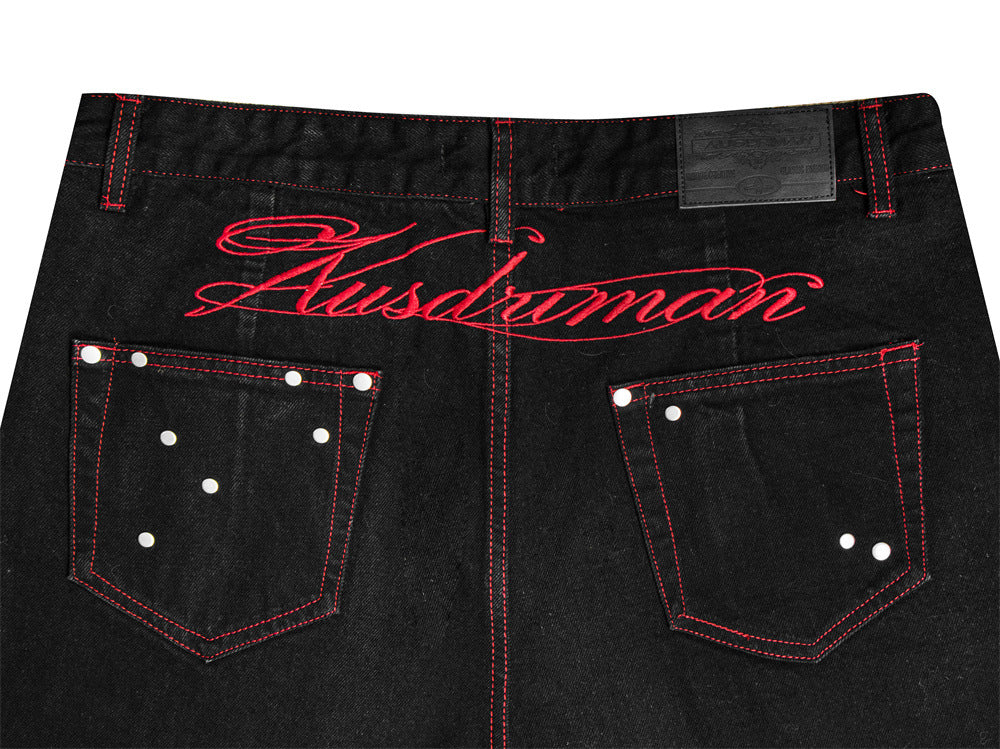 Jean homme noir à jambes larges, surpiqûres rouges contrastées, broderie étoile et clous