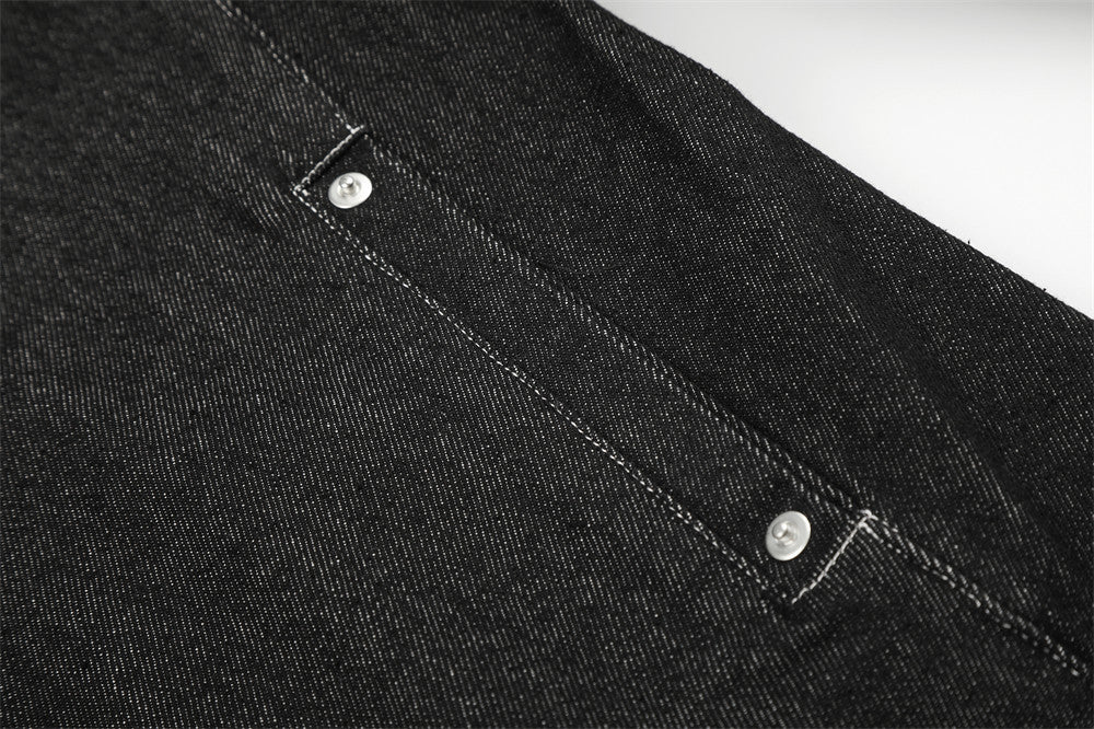 Close-up of black denim jacket side seam with silver snap detail
