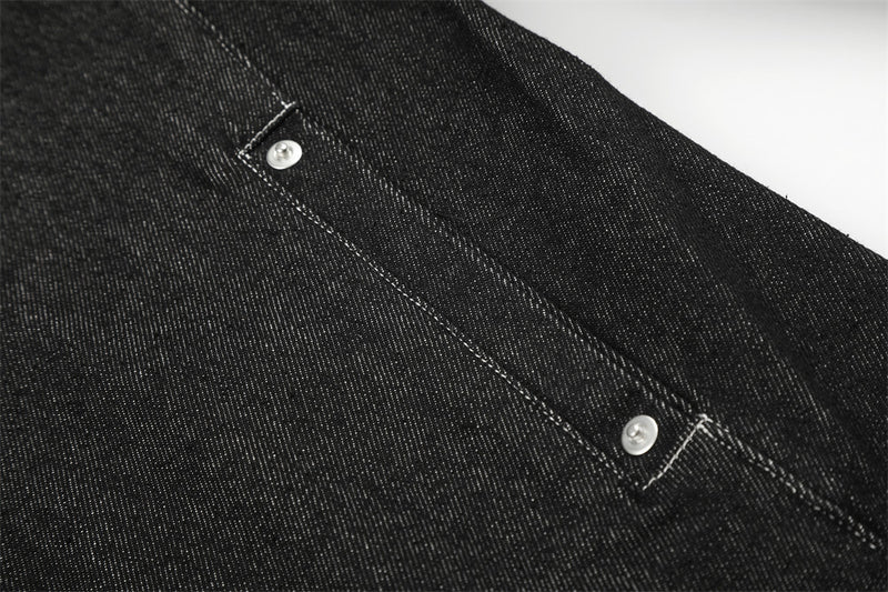 Close-up of black denim jacket side seam with silver snap detail