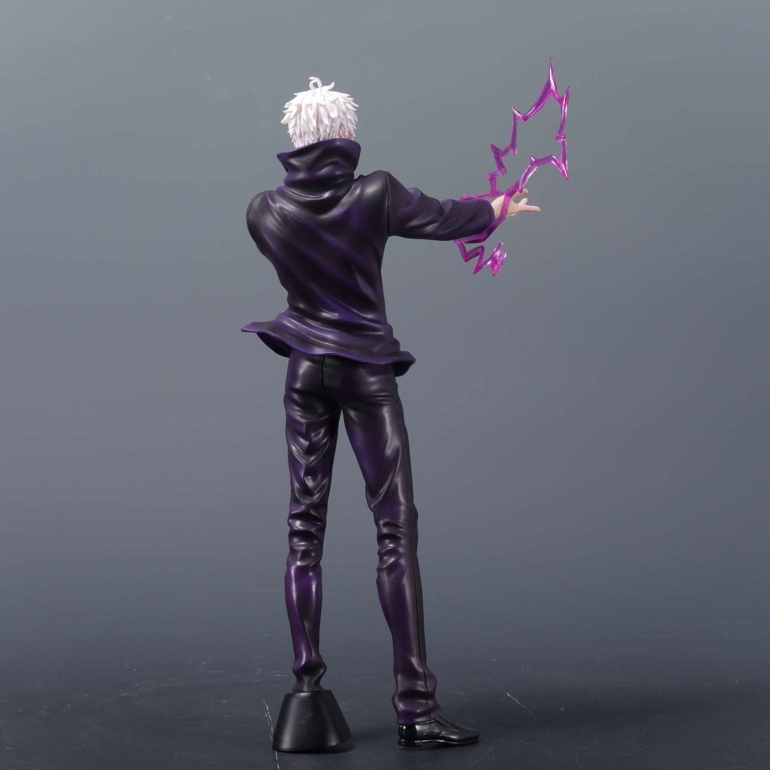 The Jujutsu Kaisen Gojo Satoru WM PVC Figure (31 cm) showcases Gojo in a dark outfit with white hair, striking a dynamic pose as he extends an arm to command a stylized pink energy bolt, hinting at the Limitless Technique. The plain gray background enhances the figure&