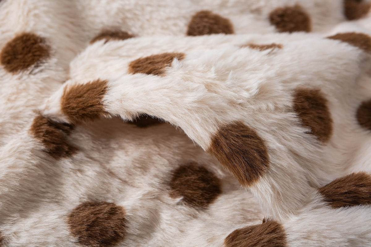 Close-up of fluffy cream faux shearling fabric with raised brown polka dots