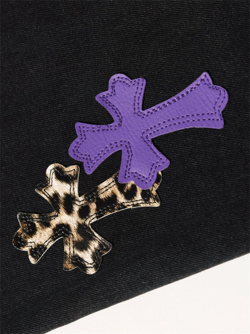 Close-up of purple and leopard cross patches on black denim, angled view