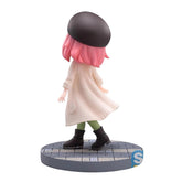 This 14 cm chibi-style Spy x Family Anya Forger PVC figure features pink hair, a black beret, a cream plaid coat, green pants, and black boots. It includes a circular base designed to look like a stone path.