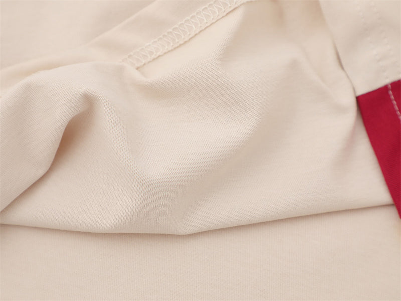 Close-up of cream shirt fabric and side seam with red panel edge