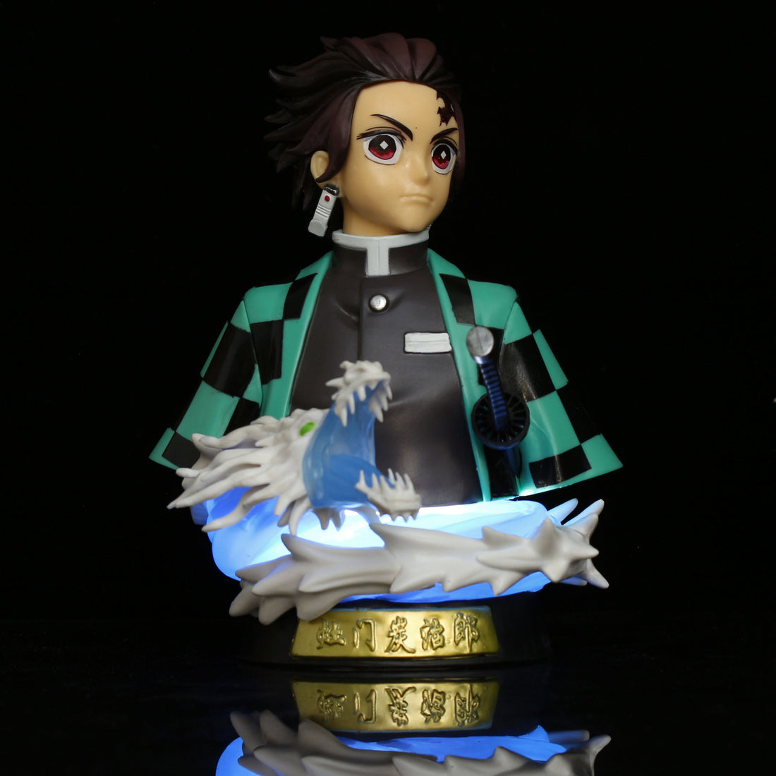 The 15cm Demon Slayer Tanjiro Kamado GK Half-Body Action Figure features spiky hair, a checkered green and black cloak, and a white dragon coiled around him. It stands on an LED-lit base with glowing blue accents, highlighting its intricate details against a black background.