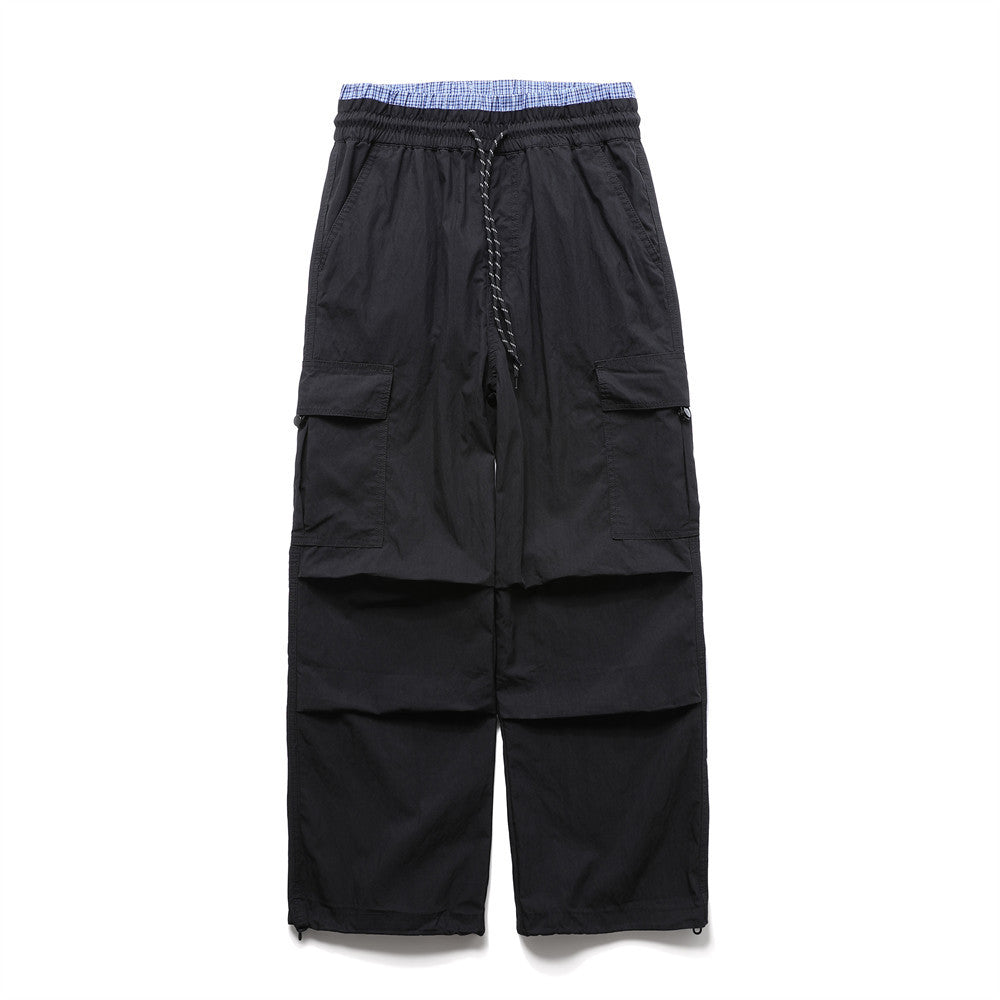 Men's wide-leg black cargo pants with double waistband, plaid inner band, drawstring, and cargo pockets