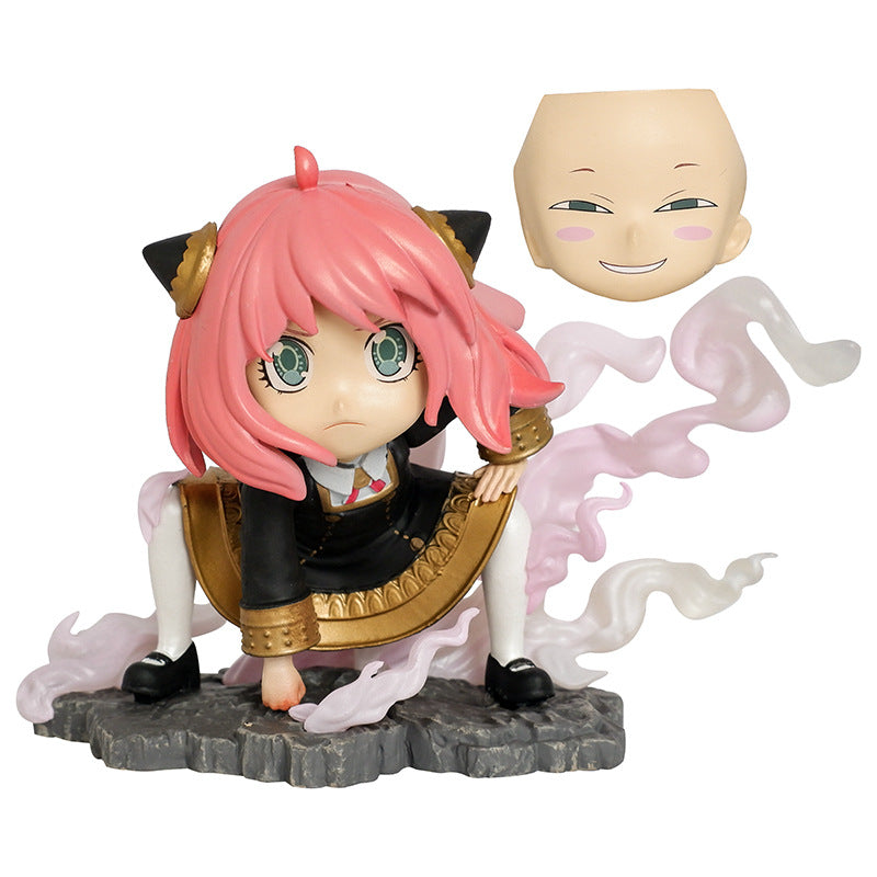 The Spy × Family Anya Forger PVC Figure features pink-haired Anya in a chibi style with cat ears and a black-gold outfit, crouched on a rocky base with swirling pink smoke. It includes a hovering interchangeable smiling bald head, inspired by Luffy Cosplay.