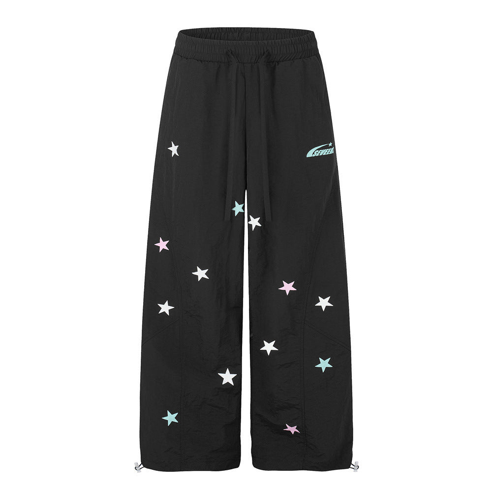 Black wide-leg parachute pants with multicolor star print and drawstring waist and hem