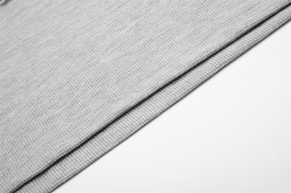 Close-up of gray tee fabric hem with visible stitched edge and waffle texture