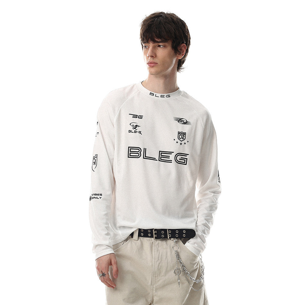 White long sleeve crew neck shirt worn by model with black racing-style logos on the chest