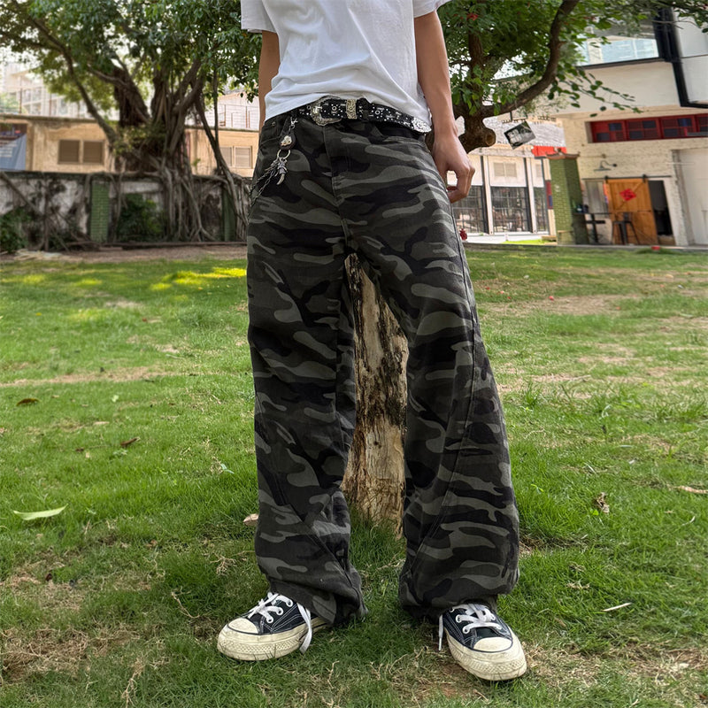 Baggy wide-leg dark green camouflage cargo pants with curved leg opening, styled with a white tee and canvas sneakers